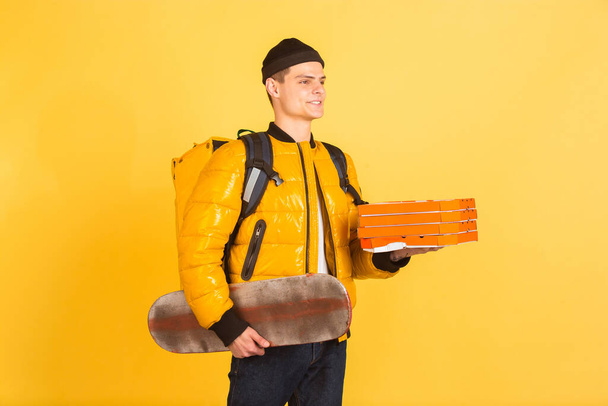 Contacless delivery service during quarantine. Man delivers food and shopping bags during insulation. Emotions of deliveryman isolated on yellow background. - Photo, image