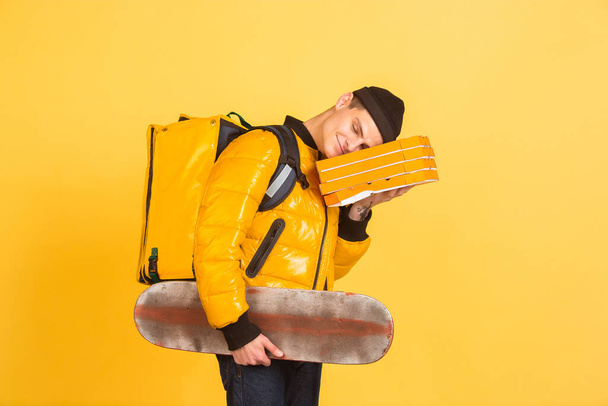 Contacless delivery service during quarantine. Man delivers food and shopping bags during insulation. Emotions of deliveryman isolated on yellow background. - Fotó, kép