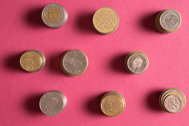 Top kilátás halom érmék különböző országokból rózsaszín háttérrel. Gyűjtsd össze a pénzt és költsd bölcsen. - Fotó, kép