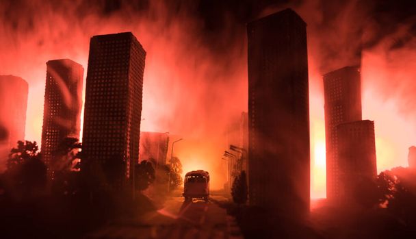 Empty street of burnt up city, flames on the ground and blasts with smoke in the distance. Apocalyptic view of city downtown as disaster film poster concept. Night scene. City destroyed by war. - Photo, Image