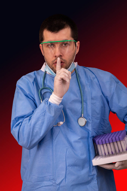 Der Arzt mit Brille, Maske und Stereoskop hält einen Schlauchständer in der Hand und bittet um Ruhe im Covid-19- oder Coronavirus-Forschungslabor - Foto, Bild