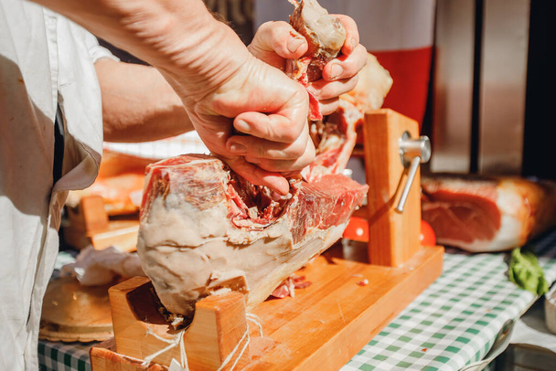O açougueiro macho corta presunto de perna de porco seco com faca no centro de Roma. Itália
 - Foto, Imagem