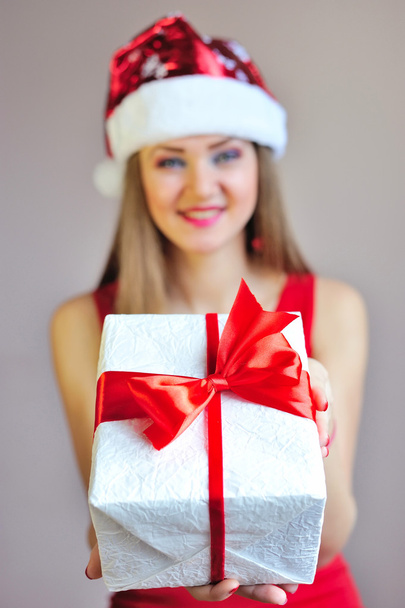 Frau hält Weihnachtsgeschenk auf der Handfläche dem Betrachter entgegen, Nahaufnahme ihrer Hand mit selektivem Fokus - Foto, Bild