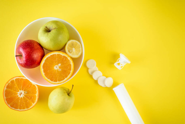 果物のトップビュープレートと散乱錠剤の横に、合成ビタミンに対する果物の選択の概念 - 写真・画像