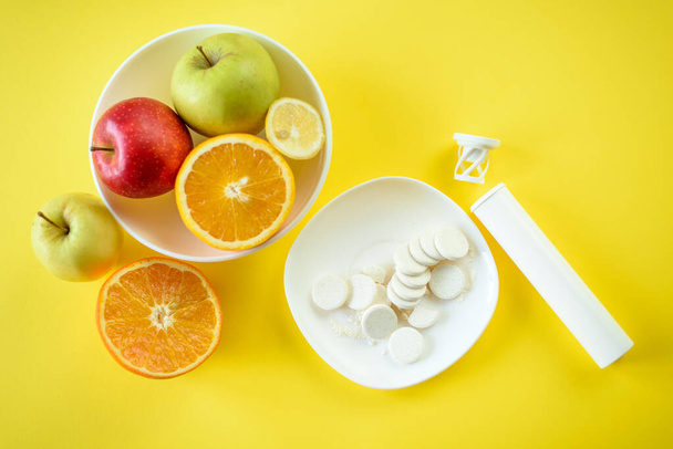 Vista superior de Frutas y medicamentos en los platos, concepto de elegir frutas frente a vitaminas sintéticas
 - Foto, Imagen