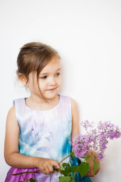 little girl in a dress with a branch of lilac, blooming branch, baby, daughter, beauty - Foto, imagen