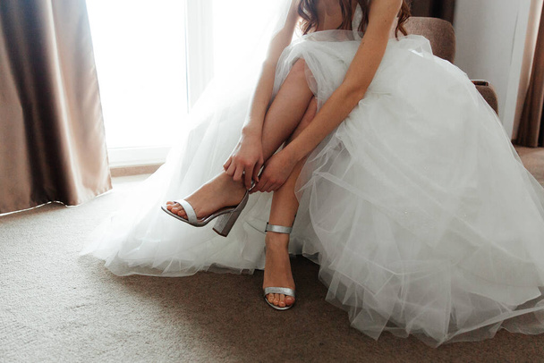 La mattina della sposa al matrimonio, alle riunioni di lusso della sposa, legano un vestito e si mettono le scarpe.
 - Foto, immagini