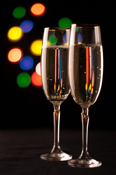 two glasses of champagne toasting against bokeh lights background - Photo, Image