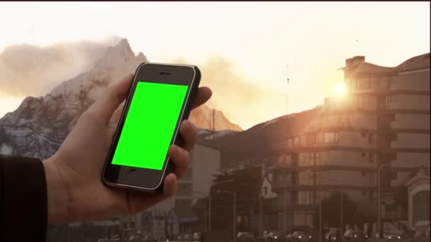 Man Hand met een oude smartphone bij zonsondergang in Ushuaia, provincie Tierra del Fuego, Argentinië. U kunt vervangen Green Screen met de Beeld of Foto die u wilt met Keying effect in After Effects (check out tutorials op YouTube).  - Video
