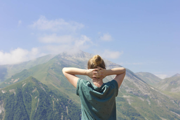 Young woman enjoys the clean air in the mountains. Tourist girl. - Фото, изображение
