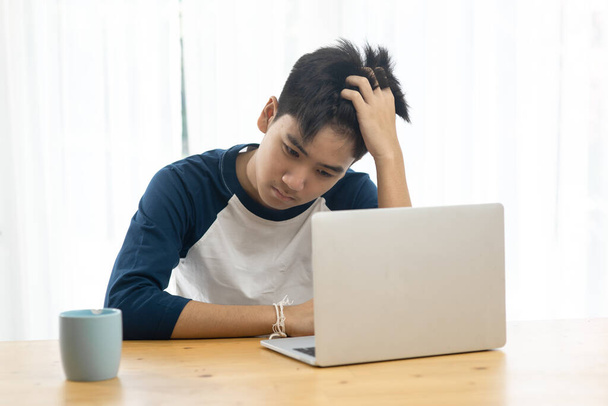 Asian teenager using and laptop for online education, headache and seriously situation. - Фото, зображення