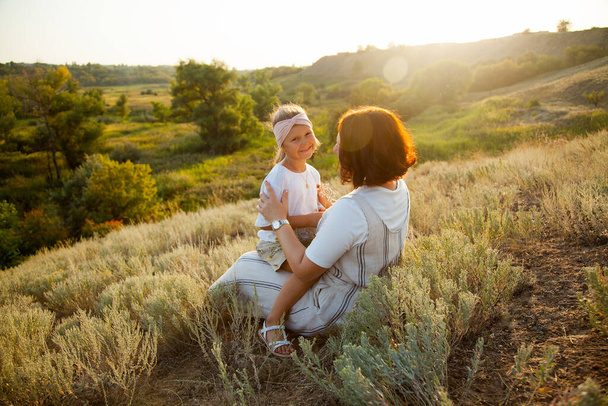 Happy mother and daugther enjoiyng in field in sunny day - Fotó, kép