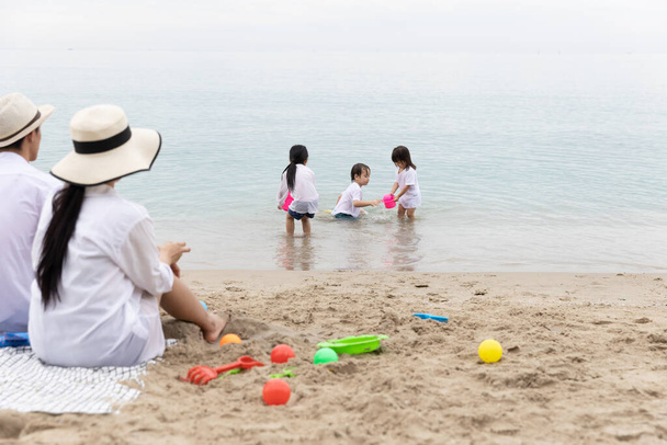 Feliz familia asiática Hermano y hermana tres jugando juguetes en la arena en la playa juntos en la mañana. Concepto de vacaciones y viajes
. - Foto, imagen