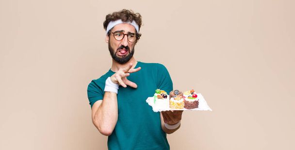 young sports man with cakes against flat wall - Zdjęcie, obraz