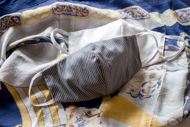 weiß-weiße und graue Gesichtsmaske auf gemustertem Schal - Foto, Bild