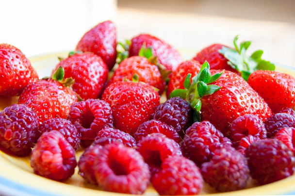 Assiette avec des baies mûres d'été - fraises, fraises, framboises. Vitamine délicieux simple végétalien naturel dessert juteux. Les arômes de l'été. Baies au soleil chaud
. - Photo, image