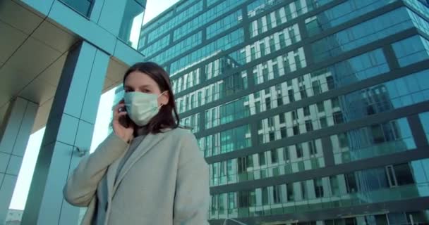 Woman in face mask talking on phone in business district - Video