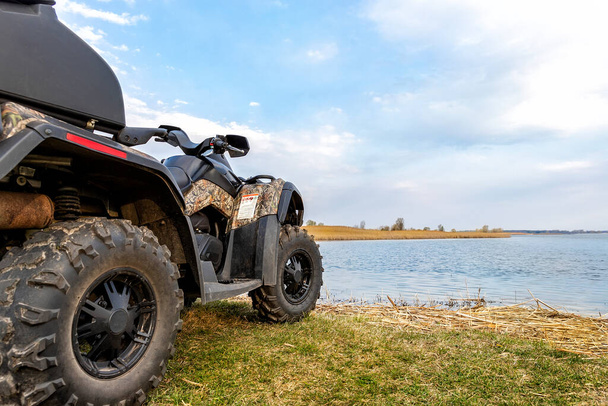 ATV awd quadbike motocykl widok punkt w pobliżu jeziora lub brzegu stawu rzecznego z pięknym krajobrazem przyrody tło nieba. Offroad podróż wyprawa przygodowa. Ekstremalna aktywność sportowa - Zdjęcie, obraz