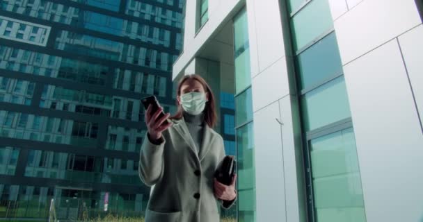 Woman in face mask talking on phone in business district - Filmmaterial, Video