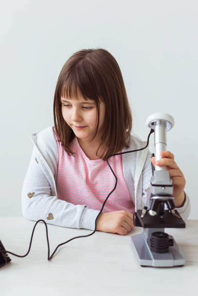 Kind meisje in de wetenschap klas met behulp van digitale microscoop. Technologieën, kinderen en leerconcept. - Foto, afbeelding