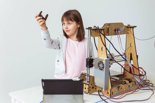 Χαριτωμένο κορίτσι με 3D εκτυπωμένες αποχρώσεις του παραθύρου παρακολουθεί 3d εκτυπωτή της, όπως εκτυπώνει 3d μοντέλο της. - Φωτογραφία, εικόνα