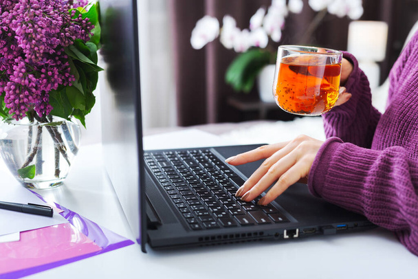 Relaxing woman working or learning from home using laptop drink tea. Freelancer have remote work, online education, work on maternity leave. Female hands typing on keyboard at home office - Zdjęcie, obraz