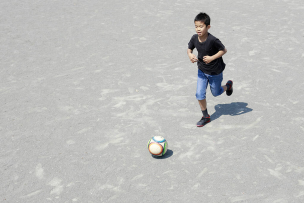 Japanischer Junge dribbelt Fußball (fünfte Klasse der Grundschule)) - Foto, Bild