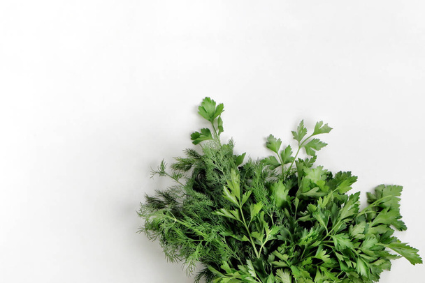 A large bunch of fresh organic green parsley, dill on a white background. Garden greens, spicy herbs, ingredients for cooking. Close-up, top view with copy space for text. - Foto, Imagen