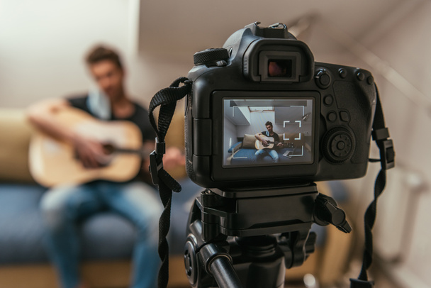 foyer sélectif de jeune vlogger jouer de la guitare tout en regardant appareil photo numérique
 - Photo, image