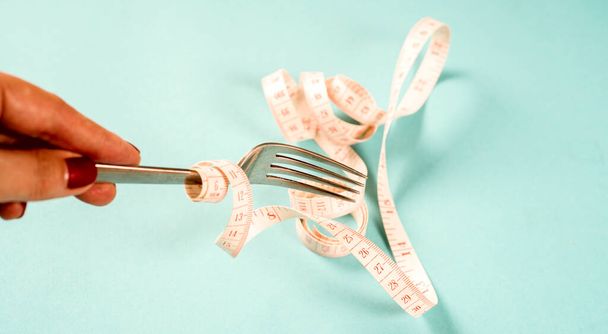 fork and knife with a centimeter on a blue background, diet, healthy lifestyle. - Foto, Bild