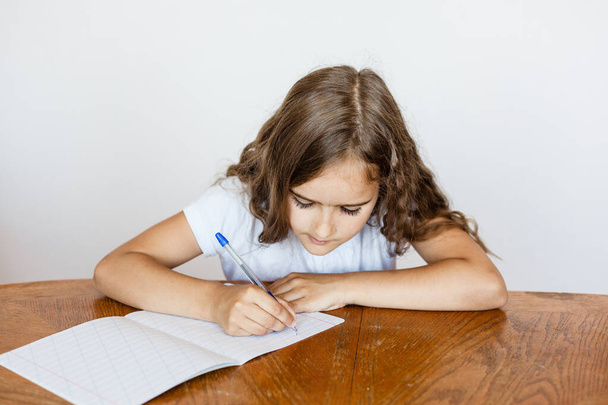 A school girl does homework at home, classes via the Internet, online, learning a foreign language, learning English, notebook, learn letters and words - Foto, Imagem