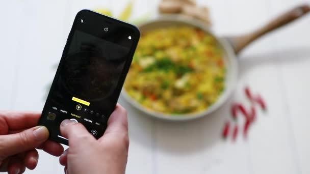 vrouw het nemen van een foto met mobiele telefoon van heerlijke gebakken rijst met kip geserveerd in pan - Video