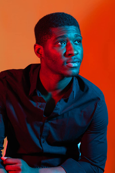 Dunkles Neon-Porträt eines jungen Mannes im Hemd. Rotes und blaues Licht. Technologie - Foto, Bild