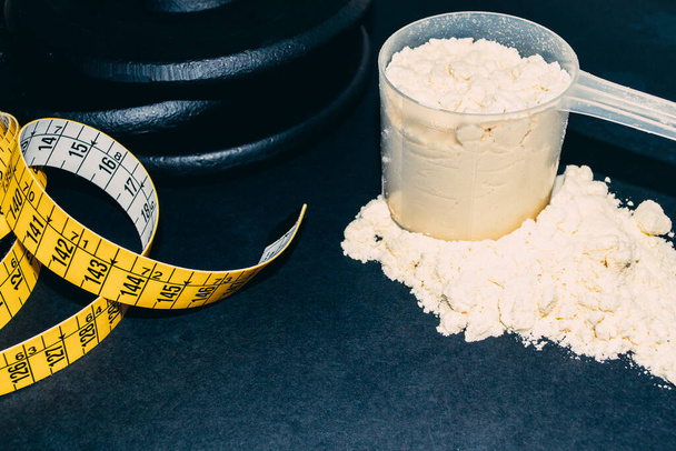 Close-up of Whey Protein Spoon Powder, with weights and tape measure. sports nutrition  - Photo, Image