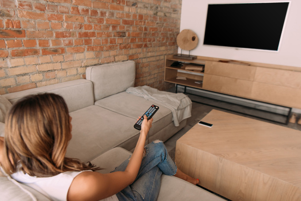 girl holding remote controller and watching tv with blank screen during self isolation, selective focus - Photo, image