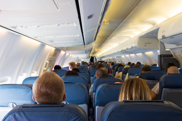 Interior of airplane with passengers on seats waiting for take off from airport. Vacation concept - Photo, image