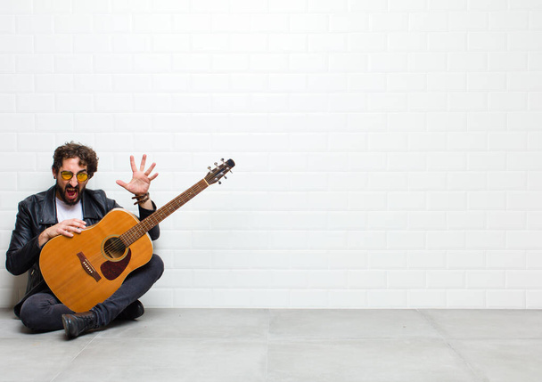 handsome man with guitar on floor in room - Фото, изображение