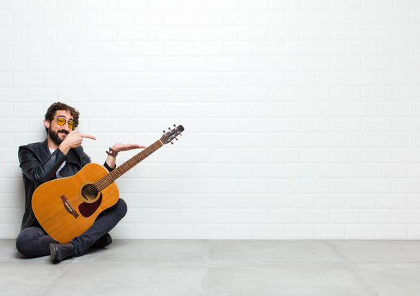 young man with guitar on floor in room - Fotó, kép
