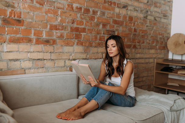 attractive girl reading book on sofa during self isolation - Photo, image
