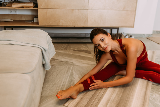 bella ragazza sorridente che si estende sul tappetino yoga a casa in quarantena
 - Foto, immagini