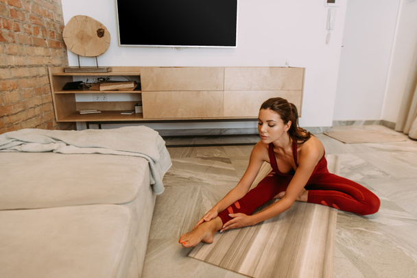 attractive girl stretching on yoga mat at home on quarantine - Fotografie, Obrázek