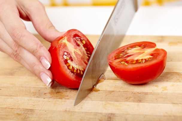 Slicing the tomato on a wooden board - Фото, изображение