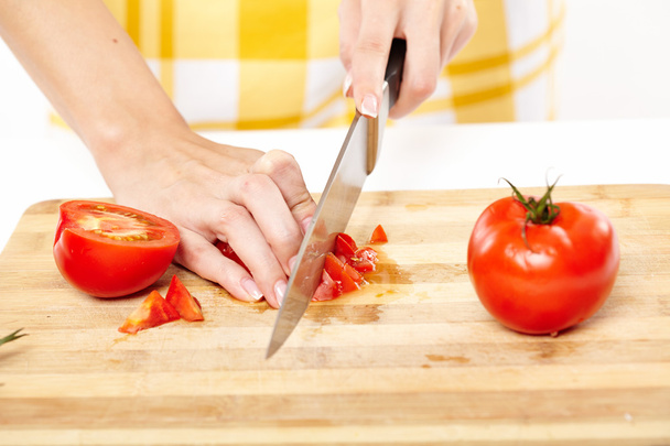 Slicing the tomato on a wooden board - Foto, imagen