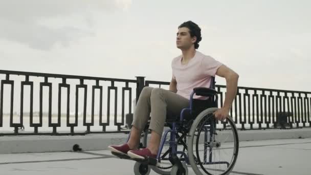 De invalide man zit in de rolstoel rijdt langs de dijk - Video