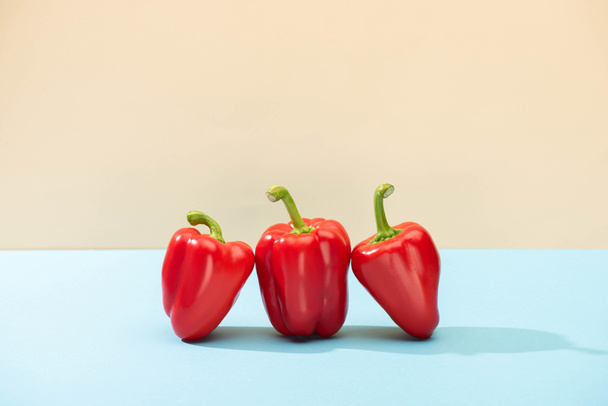 fresh red bell peppers on blue surface isolated on beige - Fotó, kép