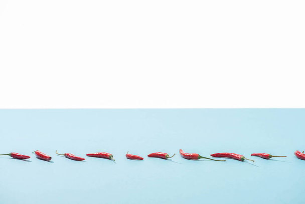 fresh red chili peppers on blue surface isolated on white - Valokuva, kuva
