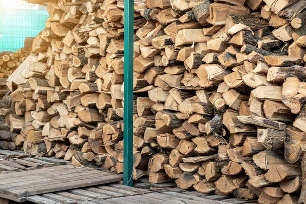 Chopped firewood storage under shed and oak wooden tree logs prepared for chopping and cutting at home backyard. Woodshed store at house yard.Timber material for heating alternative renewable energy - Φωτογραφία, εικόνα
