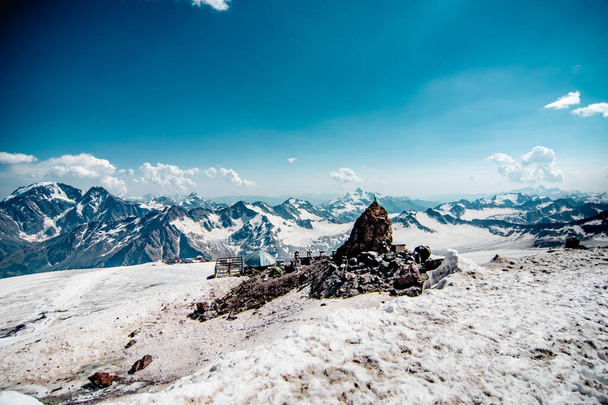 Barınak 11. Yazın yüksek dağlarda kar. Elbrus Dağı 'ndaki dağcılar için bir otel. Bulutlarda mavi gökyüzü. - Fotoğraf, Görsel