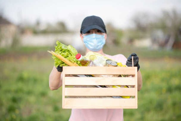 Neat hardworking courier perusing the report. young woman  with a bag of vegetables.young woman with a basket of vegetables.  Coronavirus. Woman with face mask on quarantine. Stay at home. - Фото, зображення