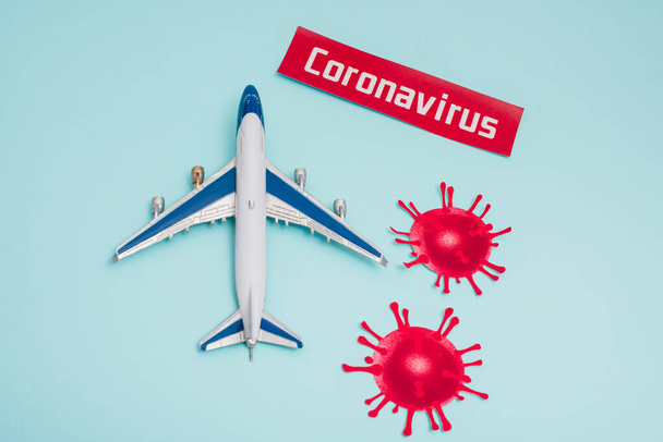 Top view of toy near card with coronavirus lettering and decorative coronavirus molecules on blue - Fotografie, Obrázek